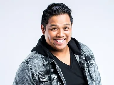 A man with black hair and a jacket smiles for the camera.