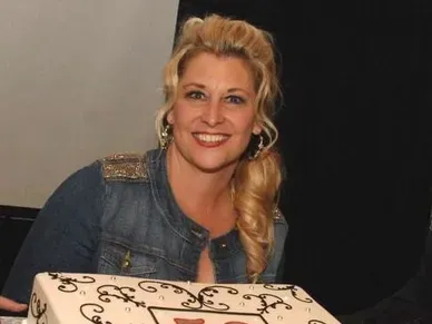 A woman sitting in front of a cake.