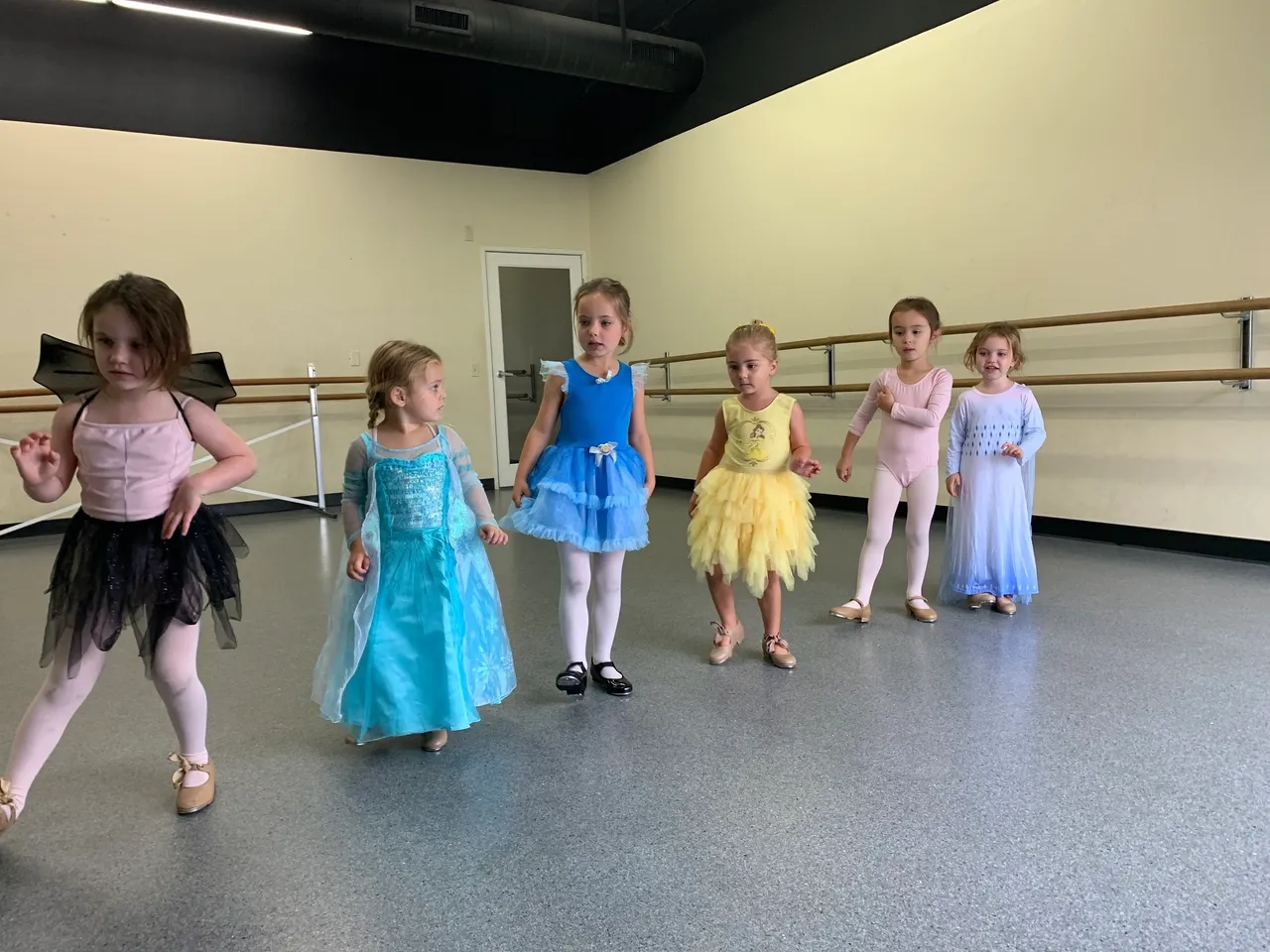 A group of young girls in costumes are practicing ballet.