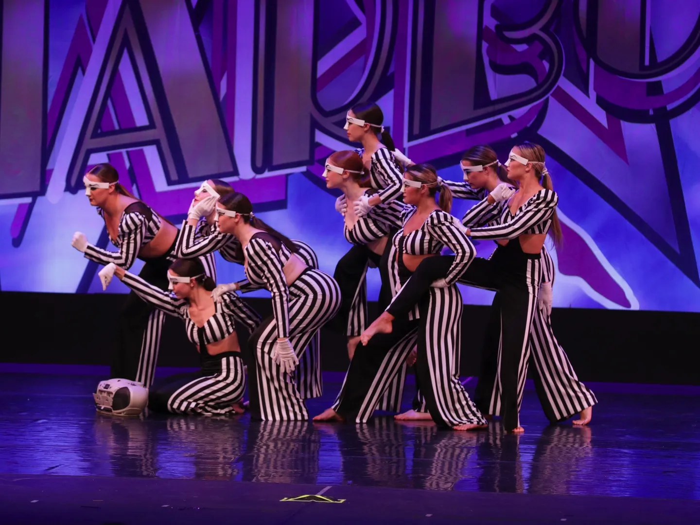 A group of dancers in striped outfits on stage.